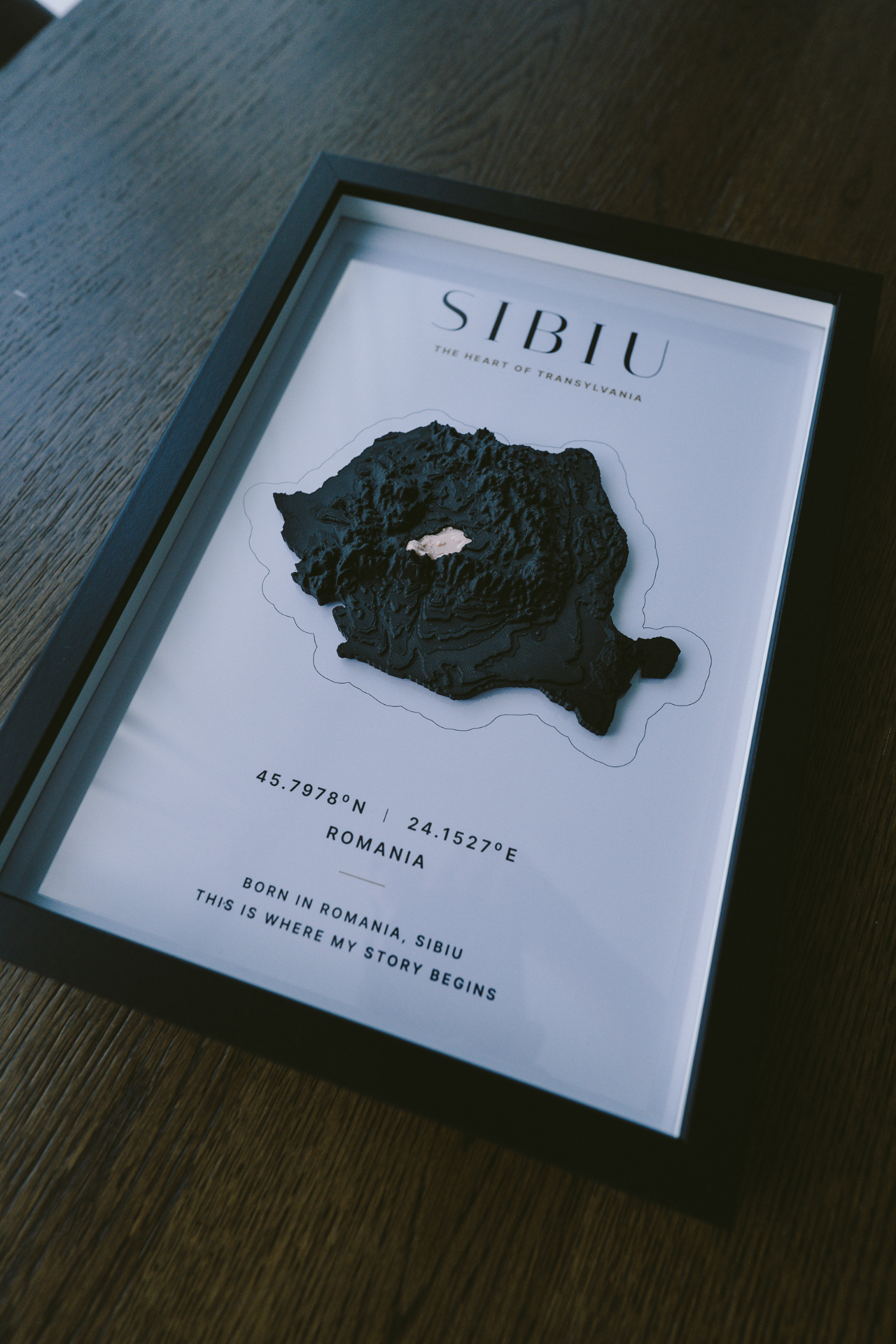 VUMO Sibiu A4 framed piece on dark oak surface